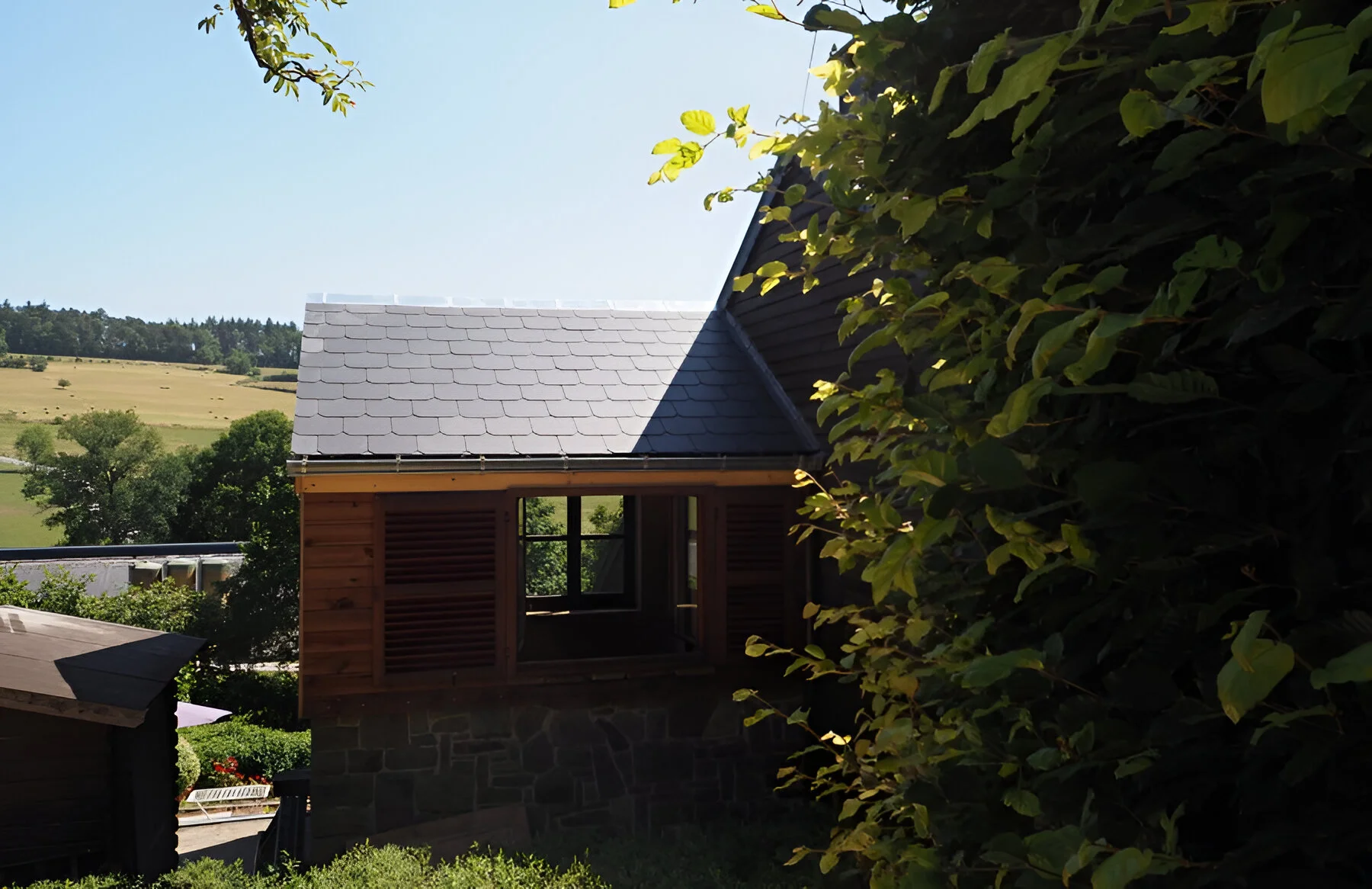 Afgewerkte aanbouw van vakantiewoning nabij Durbuy met natuurstenen muur en houten bekleding door NSS-Constructie